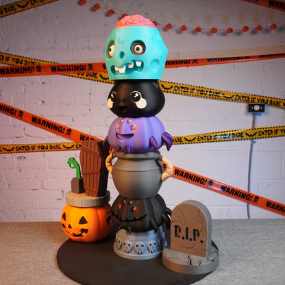 Halloween-themed toy stack with colorful characters and a pumpkin, surrounded by decorative tape.